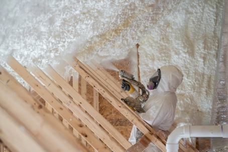 worker spraying attic insulation